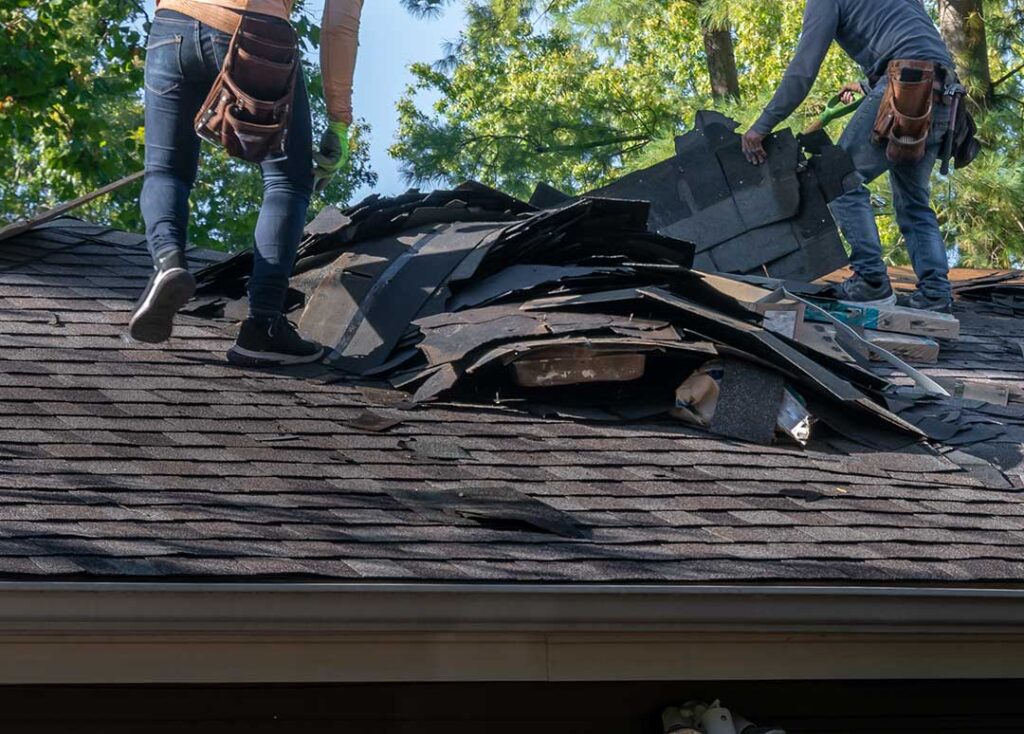 A homeowner carefully using a ladder to inspect a residential roof on a clear day.