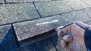 Worker secures a temporary roof covering while a resident watches from a safe distance.